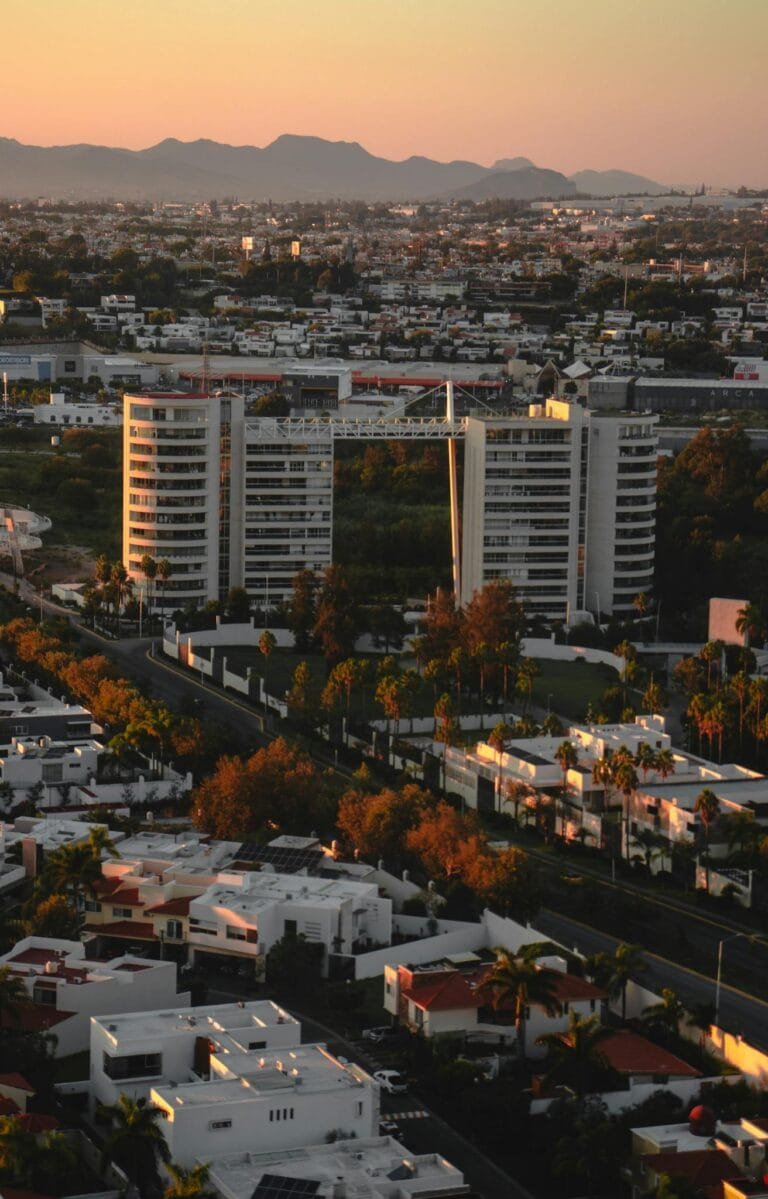 A view of a city at sunset with buildings and mountains